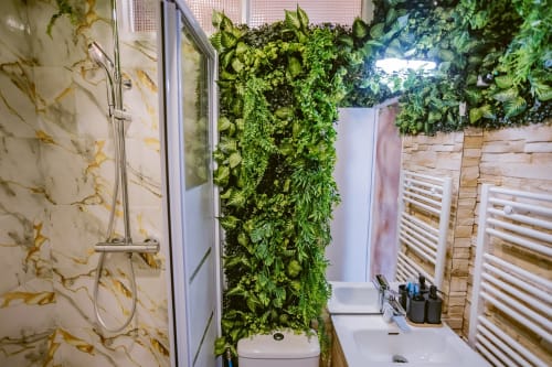 Salle de bain Jungle Room avec mur végétal, carrelage en marbre, lavabo, toilettes et sèche-serviettes chauffant aux Gîtes De Dordogne