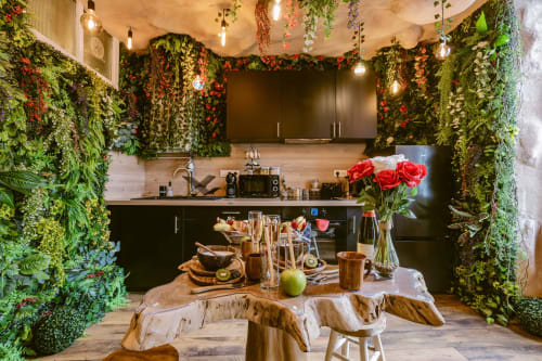 La Jungle Room aux Gîtes De Dordogne : murs vert jungle, cuisine noire, table en bois, roses rouges et fruits frais.
