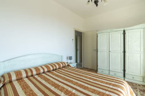 Camera luminosa in Agriturismo Il Vecchio Mulino, Terzorio, con biancheria a righe, testata azzurra e armadio bianco