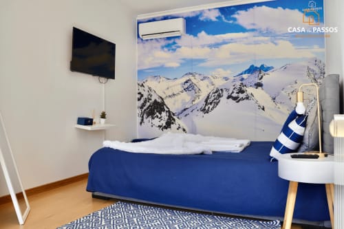Quarto moderno na Casa Dos Passos, Guarda com cama azul, painel de mural de montanha, TV e piso em madeira