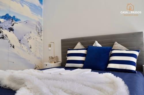 Quarto moderno em Casa Dos Passos, Guarda com almofadas azuis listradas, cabeceira cinzenta e arte de montanhas nevadas