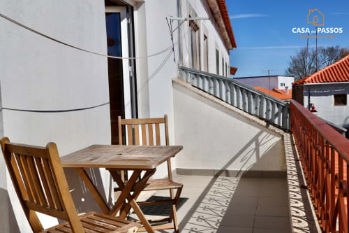 Terraço de Casa Dos Passos em Guarda com mobiliário de madeira e vista para a arquitetura portuguesa sob céu azul