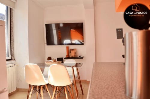 Sala de estar moderna em Casa dos Passos, Guarda com mesa de jantar, cadeiras brancas, TV na parede e iluminação aconchegante
