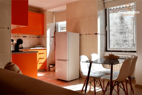 Cozinha e sala de jantar modernas no apartamento Casa Dos Passos, Guarda. Com armários laranja, mesa de jantar e ambiente luminoso