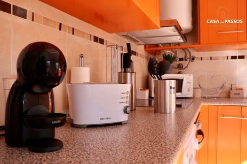 Cozinha moderna do apartamento Casa Dos Passos na SM Stays Collection em Guarda com móveis laranja e aço inoxidável