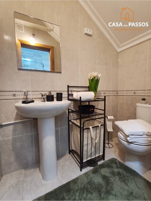 Casa de banho moderna no apartamento Casa dos Passos em Guarda, Portugal com lavatório, sanita e prateleira de metal preto