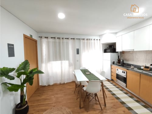 Moderna área de cozinha-sala de jantar no apartamento Casa Dos Passos, Guarda, com armários de madeira, mesa de jantar e janelas claras