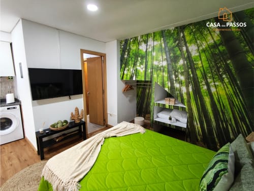 Quarto da Casa dos Passos em Guarda com roupa de cama verde, TV, painel de floresta de bambu e comodidades modernas