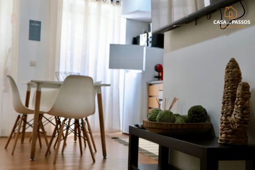 Interior moderno e luminoso de apartamento com área de refeições, cadeiras nórdicas, piso de madeira e plantas decorativas na Casa Dos