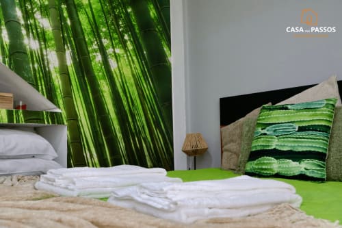 Quarto do apartamento Casa Dos Passos em Guarda com papel de parede de floresta de bambu, roupas de cama brancas, detalhes verdes e móveis modernos