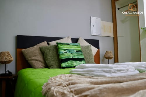 Quarto moderno na Casa Dos Passos em Guarda com roupa de cama verde, almofadas decorativas e iluminação natural