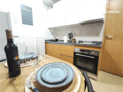 Cozinha e sala de jantar modernas no apartamento Casa Dos Passos, Guarda, com mesa posta e garrafa de vinho