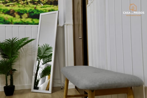 Quarto moderno do Casa Dos Passos em Guarda com banco estofado cinzento, espelho, planta em vaso e painéis brancos
