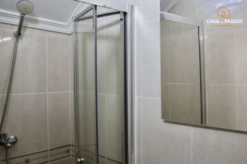 Moderno chuveiro com portas de vidro e paredes em tons bege na Casa Dos Passos, Guarda
