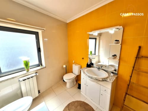Casa Dos Passos em Guarda: banheiro luminoso com azulejos laranja, bancada branca e vista da cidade