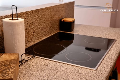 Bancada moderna da cozinha em Casa Dos Passos, Guarda, com fogão de indução, suporte de papel e painel de cortiça