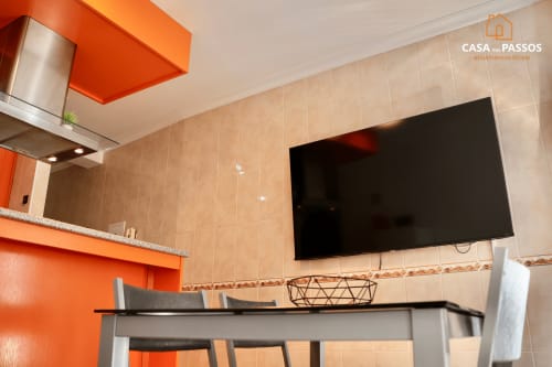 Cozinha-sala de jantar moderna em Casa Dos Passos, Guarda, com detalhes em laranja, TV de tela plana e mesa de refeições