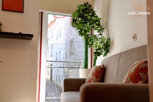 Aconchegante sala de estar da Casa Dos Passos em Guarda com vista da cidade, móveis confortáveis e planta junto à janela
