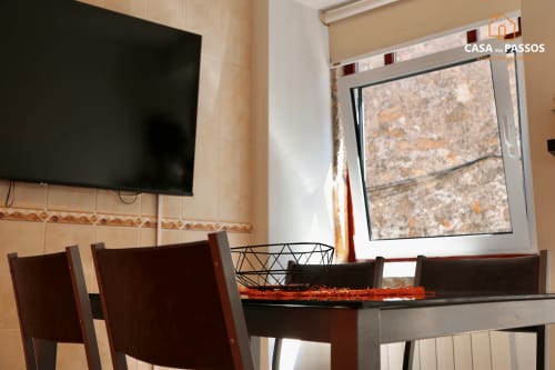 Sala de jantar do apartamento Casa Dos Passos com TV de ecrã plano, cadeiras em madeira escura e vista para a janela em Guarda