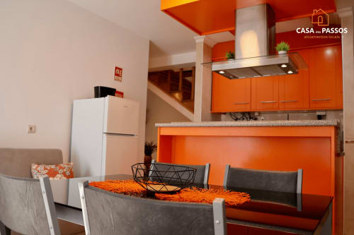 Apartamento Casa Dos Passos em Guarda com cozinha laranja vibrante, mesa de jantar e eletrodomésticos modernos
