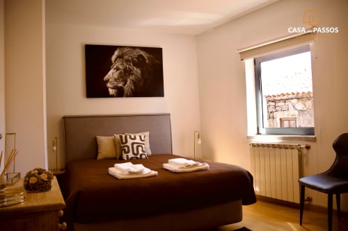 Quarto aconchegante na Casa Dos Passos em Guarda com cama de casal, obra de arte com leão e vista da cidade