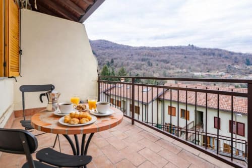 Colazione in terrazza all'appartamento Como Holiday con vista sulle montagne, pasticceria, caffè e succo con vista sulla campagna italiana