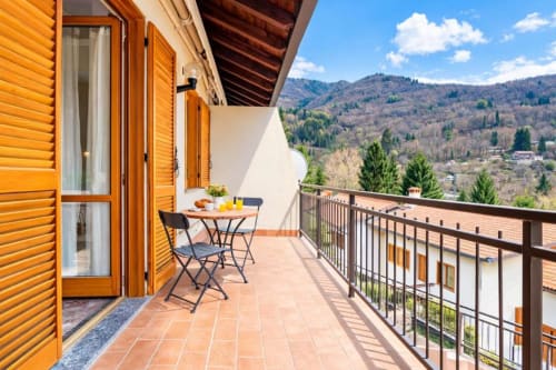 Balcony of Residenza Vecchio Faggeto apartment in Como with mountain views, dining table, and wooden railings