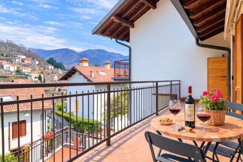 Mountain view balcony at Como Holiday apartment with wine, flowers, and Chianti landscape backdrop