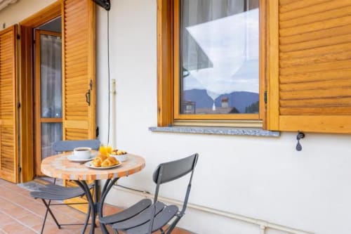 Cozy balcony seating at Como Holiday apartment with mountain views, coffee, and pastries