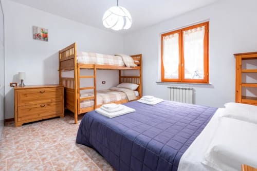 Spacious bedroom at Como Holiday with wooden bunk bed, double bed with purple quilt, and mountain views