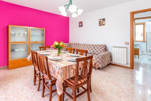 Bright dining room with wooden table, chairs, and flowers at Como Holiday apartment in Italy