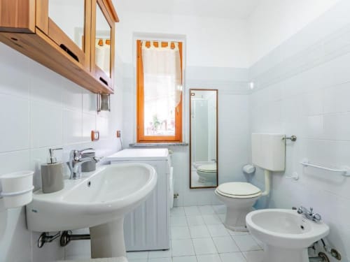 Modern bathroom in Como Holiday apartment with sink, bidet, toilet, and white tile walls with mountain view window