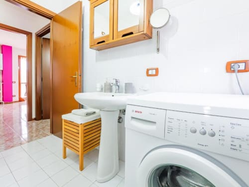 Modern bathroom with washing machine, sink, and wooden cabinet in Como apartment Residenza Vecchio Faggeto