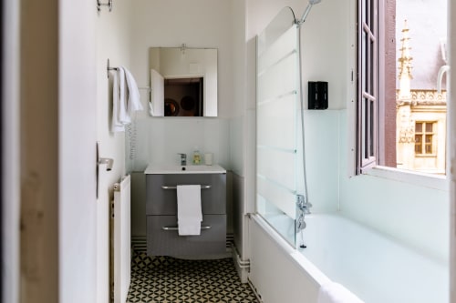 Modern bathroom in Chambre 5 at Hôtel les Initiés, Rouen, with dark vanity, mirror, and glass shower enclosure overlooking