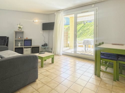 Séjour moderne avec télévision, mobilier vert et accès à la terrasse avec vue sur les montagnes au Vallon des Sources,