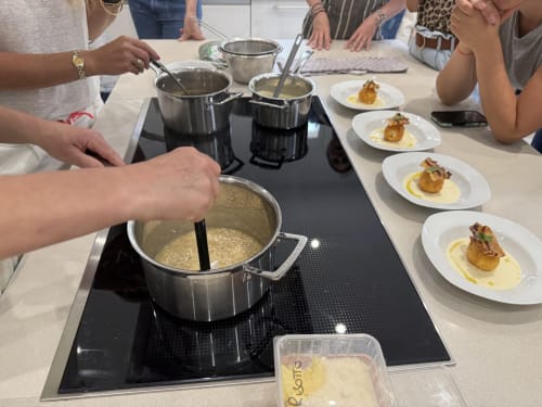 Cooking class at Domaine de Bize showing hands preparing risotto with plated scallop dishes at Mirepoix hotel