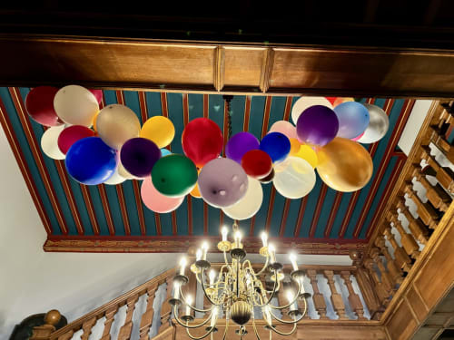 Colorful balloons decorate ornate ceiling with chandelier at Domaine de Bize Mirepoix Manor