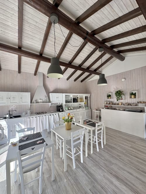 Modern kitchen and dining area at La Dolce Casa B&B in Cremia with white cabinetry, exposed beams, and pendant lighting