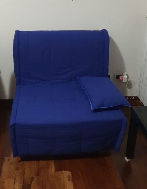 Sedia blu con cuscino nella suite House Olgiata dell'hotel Myob, pavimento in legno e pareti bianche