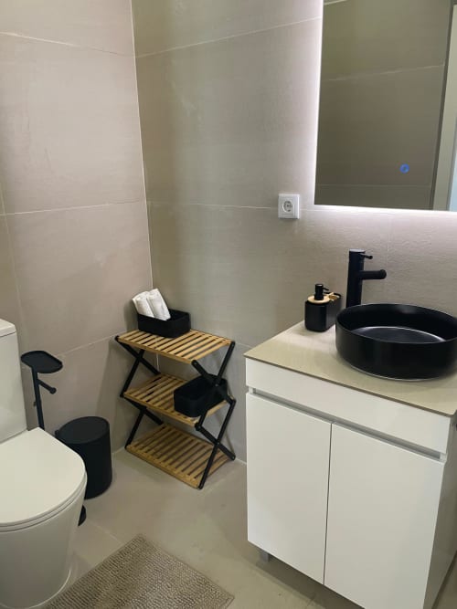 Banheiro moderno do apartamento Casa Da Avó Ilda em Matosinhos com cuba preta, gabinete branco, sanitário e prateleira de madeira