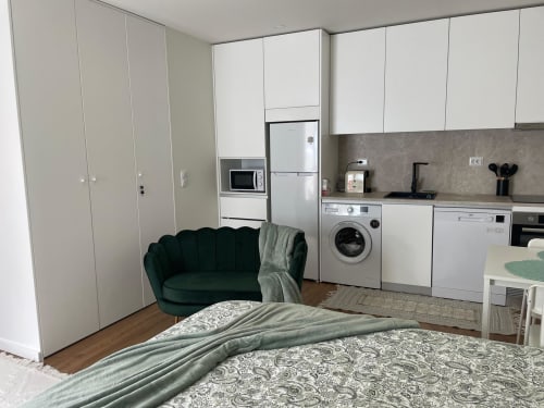 Studio em Casa Da Avó Ilda, Matosinhos: cama, poltrona verde, cozinha equipada e móveis brancos