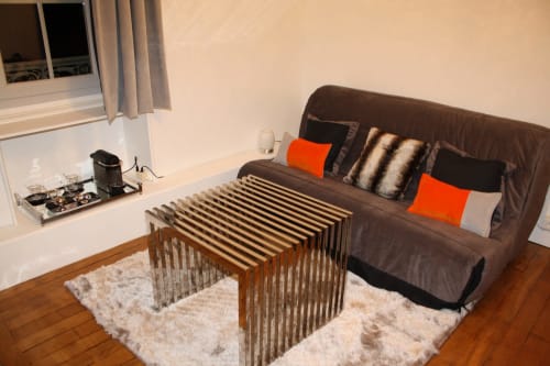 Suite moderne du Relais Du Destin Vertrieu avec canapé marron, table basse en bois, tapis crème et vue sur les fenêtres