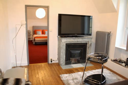 Suite moderne au Relais Du Destin à Vertrieu avec cheminée, télévision, parquet et accès à une chambre aux touches orangées