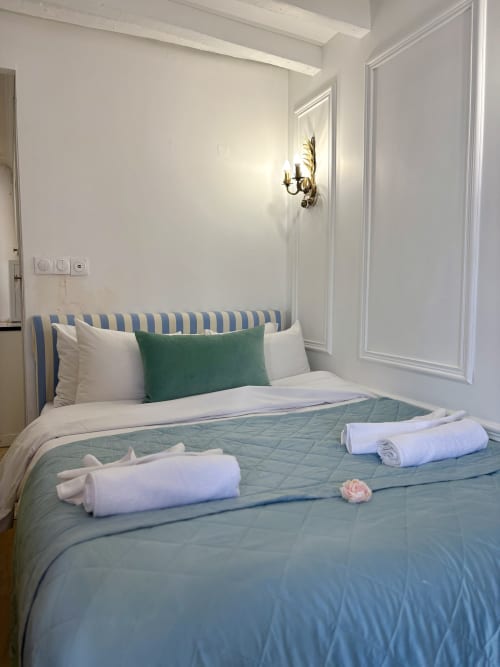 Habitación elegantemente decorada en ALDARO Paris con cabecero de rayas azules, toallas enrolladas y flores frescas