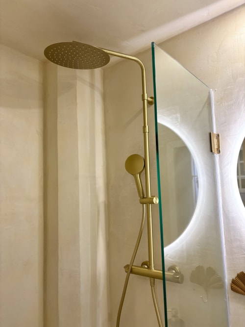 Cabezal de ducha tipo lluvia en latón moderno y alcachofa manual en baño de apartamento parisino contemporáneo con mampara de vidrio