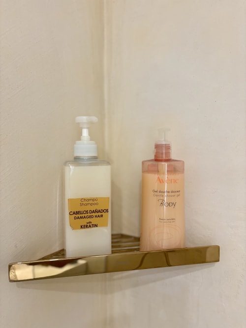Amenities del baño en repisa de latón: champú de keratina para cabello dañado y gel de ducha suave Avène en apartamento parisino