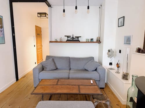 Salon moderne d'appartement avec canapé gris, table en bois et étagères suspendues à l'hôtel La Rochelle