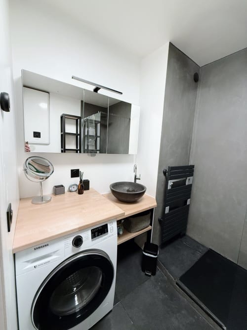 Salle de bains moderne de l'appartement Maison ARLOÉ La Rochelle avec lave-linge, meuble vasque en bois et lavabo rond