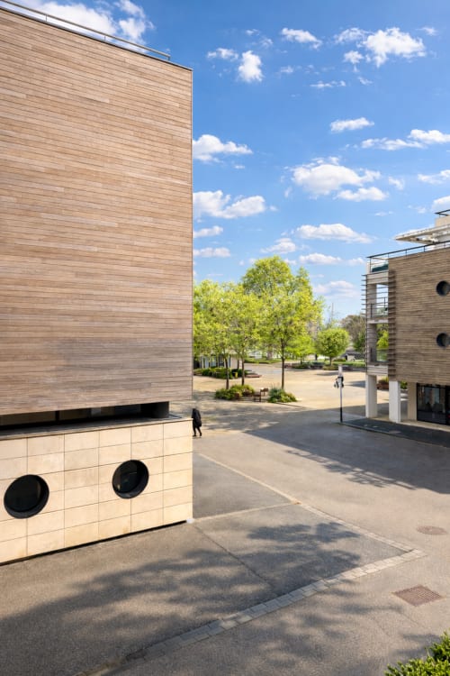 Cour moderne de la Maison ARLOÉ à La Rochelle avec façades en bois, verdure et ciel dégagé