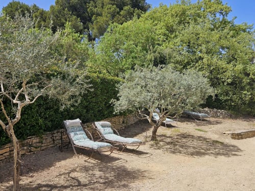 Sonnige Loungeecke mit gestreiften Polsterstühlen zwischen Olivenbäumen im Ferienhaus Gordes